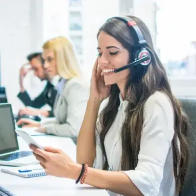 A woman wearing a headset, focused on her work in a modern office environment.
