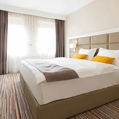 A neatly made bed in a stylish hotel room, featuring crisp white linens and decorative pillows.
