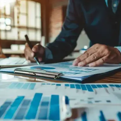 Businessman in a suit and tie reviewing financial documents at a desk, focused on his work.