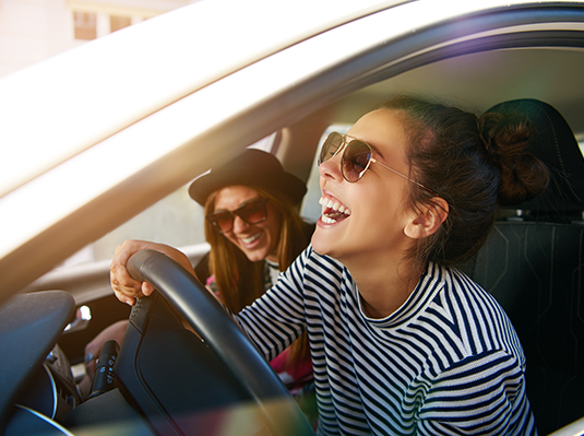 two girls laughing inside a car