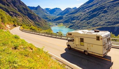 RV traveling on a road near body of water